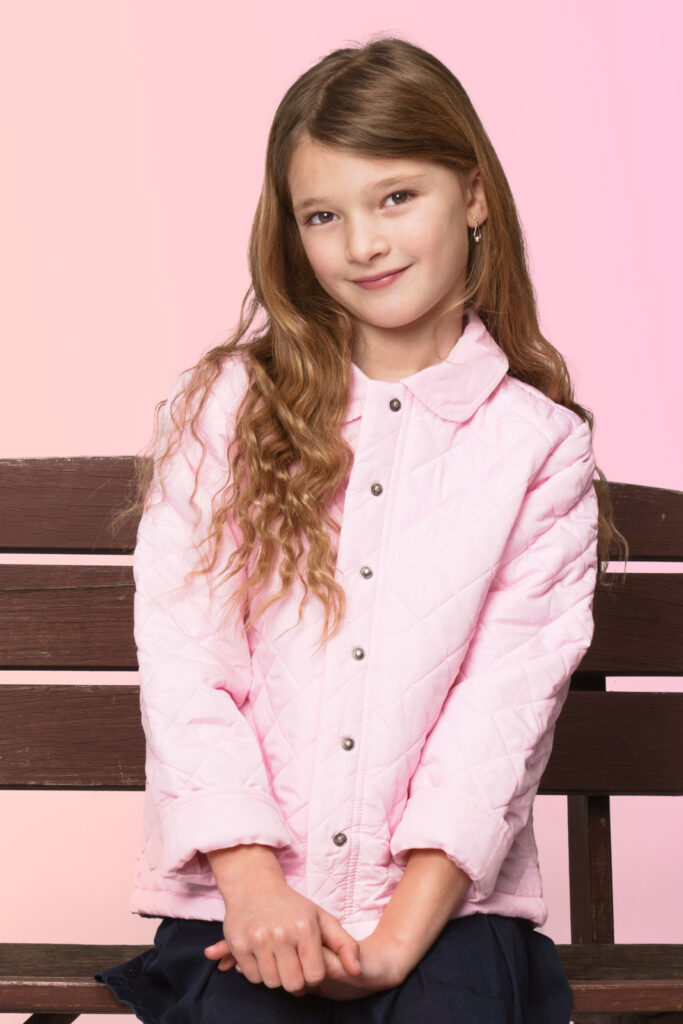 Child sitting on bench wearing fashion jacket