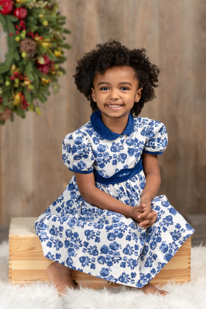 Child sitting on apple box with fashion designer dress